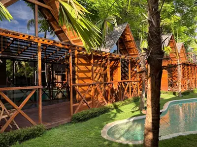 a log cabin with a pool in front of a house at Cozy Lagoon Bungalows & Pool in Nusa Dua