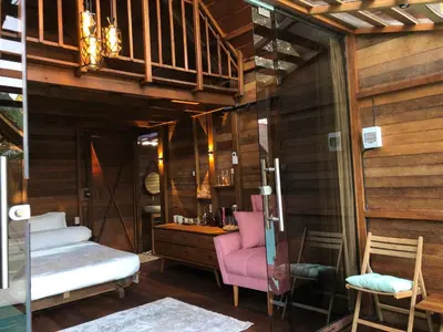 a room with a pink chair and a wooden wall at Cozy Lagoon Bungalows & Pool in Nusa Dua
