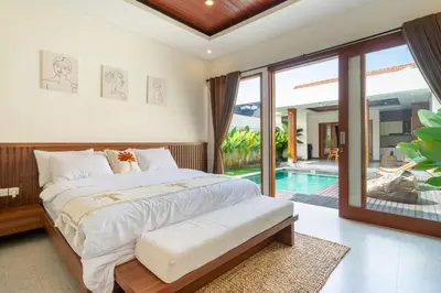 a bedroom with a large bed and a swimming pool at Modern 2BR Umalas Villa with Private Pool & Garden in Kerobokan