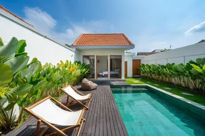 a villa with a swimming pool and two chairs at Modern 2BR Umalas Villa with Private Pool & Garden in Kerobokan