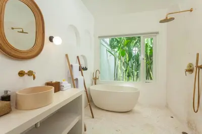 a bathroom with a large tub and a mirror at Adhya Villa by GenuineHost in Kerobokan