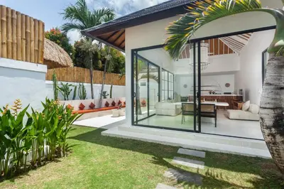 a house with glass doors and a yard at Adhya Villa by GenuineHost in Kerobokan