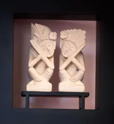 two ivory statues of two people on a shelf at Villa Alma in Legian