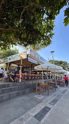 people sitting at a restaurant with tables and umbrellas at Jayakarta Bali Apartments in Seminyak