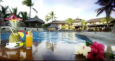 a resort pool with a drink and flowers on a table at Jayakarta Bali Apartments in Seminyak