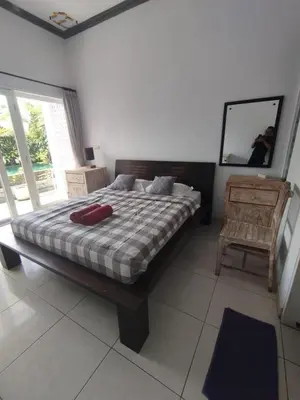 a bedroom with a bed and a mirror and a chair at sari uma in Seminyak
