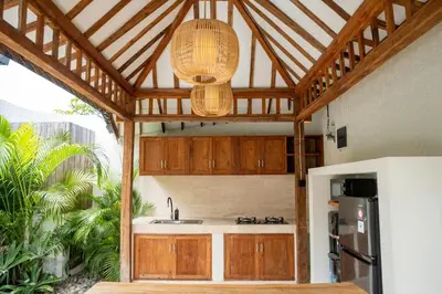 a kitchen with wooden cabinets and a sink and a chandelier at Tuluscoliving Villa Kuta 4, 2 Bedroom & 2 Bathroom in Ngurah Rai International Airport