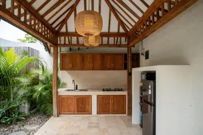 a kitchen with wooden cabinets and a sink and a refrigerator at Tuluscoliving Villa Kuta 4, 2 Bedroom & 2 Bathroom in Ngurah Rai International Airport