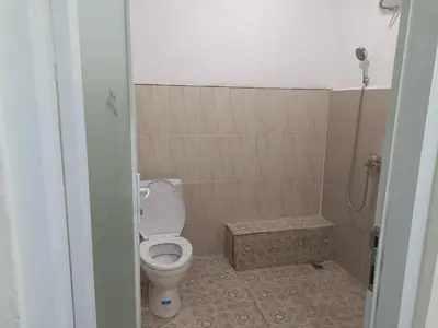 a small bathroom with a toilet and a shower at Dongsoul Guest House in Legian