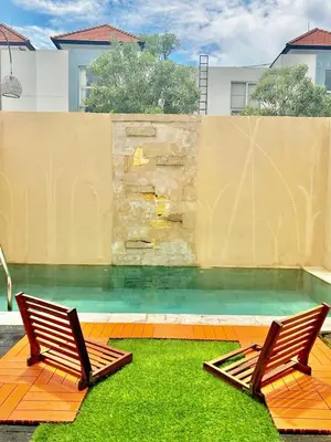 two chairs sitting on the grass next to a swimming pool at Uma Mari Villa Seminyak in Seminyak