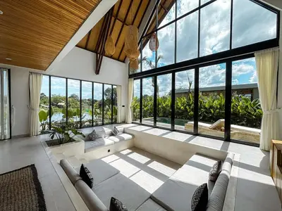a living room with a couch and large windows at Desa Hut - 2BR Tropical Ricefield Villa near Seminyak in Kerobokan