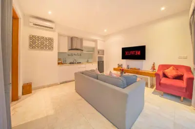 a living room with a couch and a red chair at Daiva Comfortable 1 BR Private Pool Villa in Jimbaran