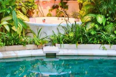 a bath tub in a garden next to a swimming pool at Alora Comfortable 1 BR Smart Pool Villa With Jacuzzi in Seminyak
