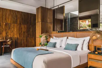 a bedroom with a large bed with a wooden wall at Charity Stunning Grand 1 BR Pool Villa With Jacuzzi in Seminyak