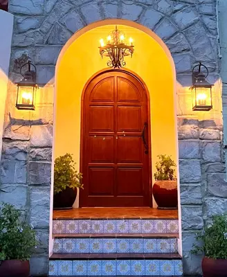 a large wooden door in a stone building with lights at Casa Mañana Villa Legian, Kuta in Legian