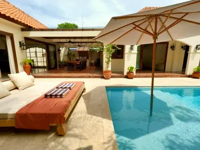 a swimming pool with an umbrella and a chaise lounge at Casa Mañana Villa Legian, Kuta in Legian
