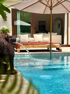 a swimming pool with a bed and an umbrella at Casa Mañana Villa Legian, Kuta in Legian