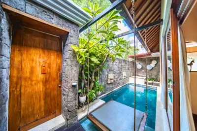 a swimming pool in a house with a wooden door at Edna Royal 1 BR Private Pool Villa With Jacuzzi in Legian