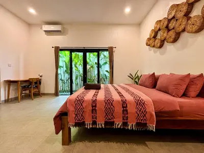 a bedroom with a bed with a red blanket and a table at Soane Summer House by AGATA in Seminyak