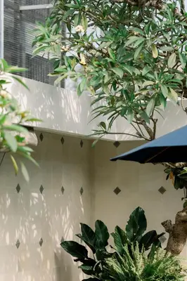 a white wall with plants and a blue umbrella at Modern 2BR Pool Villa in Umalas with Billiard & Long Pool in Canggu