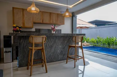 a kitchen with two bar stools and a swimming pool at Villa Inges 2 Seminyak in Seminyak