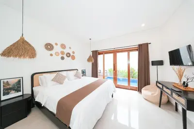 a white bedroom with a bed and a television at Villa Harmaka 2 in Kerobokan