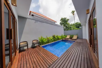 a backyard with a swimming pool and a wooden deck at Villa Harmaka 2 in Kerobokan