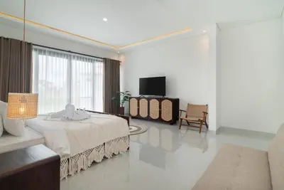 a white bedroom with a bed and a tv at Villa nia gray 1 in Seminyak