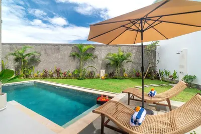 a pool with an umbrella and two chairs and a table with an umbrella at Villa nia gray 1 in Seminyak