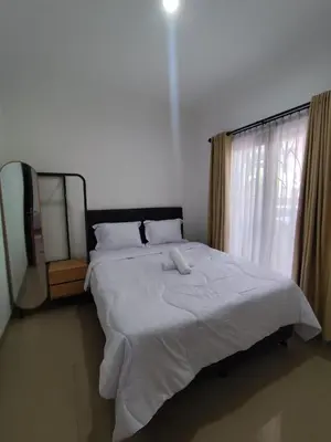 a bedroom with a large white bed with a window at salah in Nusa Dua