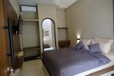 a bedroom with a bed with purple sheets and a mirror at Avaya Boutique Hostel by Ayodya Beach Inn in Legian