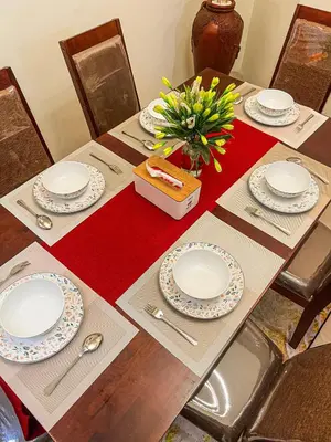 a table with plates and a vase of flowers on it at Private 5BR Jimbaran House with Pool, up to 12 Pax in Jimbaran