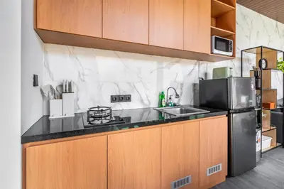 a kitchen with wooden cabinets and a black counter top at Casa Benita 2 Villa Seminyak in Seminyak
