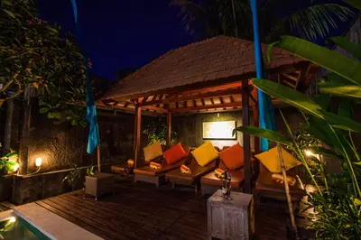 a porch with couches on a deck at night at Villa Efes Bali in Seminyak
