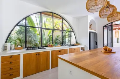 a kitchen with an arched window and a large kitchen island at Ashlyn Elegant 4 BR Private Pool Villa in Canggu
