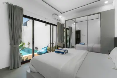 a bedroom with a large white bed and a pool at Villa Paoua by BaliSuperHost in Seminyak