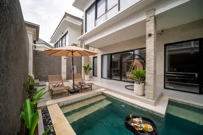 a house with a swimming pool and an umbrella at Villa Amani Seminyak in Seminyak