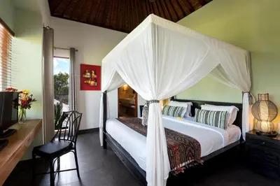 a bedroom with a canopy bed with a desk and a chair at Villa Abagram Anam in Seminyak