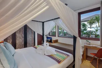 a bedroom with a bed with curtains and a desk at Villa Abagram Anam in Seminyak
