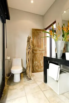 a bathroom with a toilet and a wooden door at Seminyak Villa in Seminyak