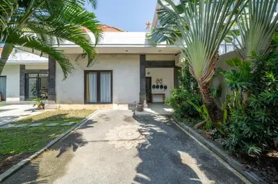 a house with palm trees in front of it at Villa Tanaka Spacious Family Villa Berawa in Canggu