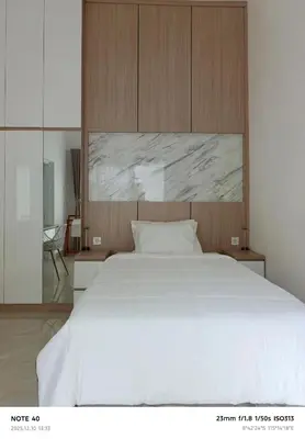 a bedroom with a large white bed with a wooden headboard at Khrisna Sanur Villa in Pesanggaran