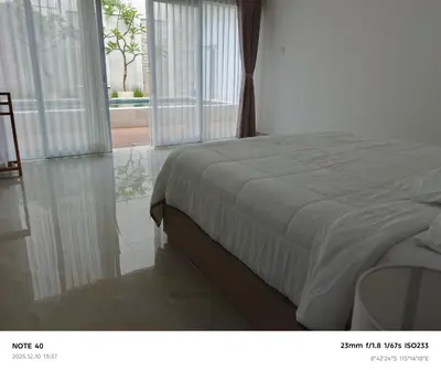 a bedroom with a bed and a large window at Khrisna Sanur Villa in Pesanggaran