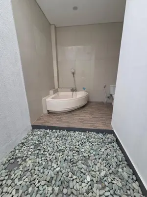 a bath tub in a bathroom with rocks on the floor at Vila Hokyusa in Kerobokan