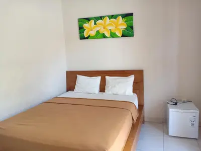 a bed in a room with a painting on the wall at Pondok Hokyusa in Seminyak