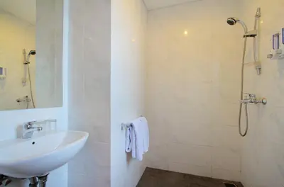a white bathroom with a sink and a shower at Vansari Hotel in Seminyak