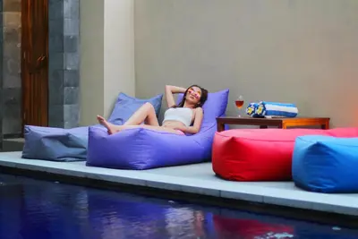 a woman laying on alatable bed next to a pool at Vansari Hotel in Seminyak