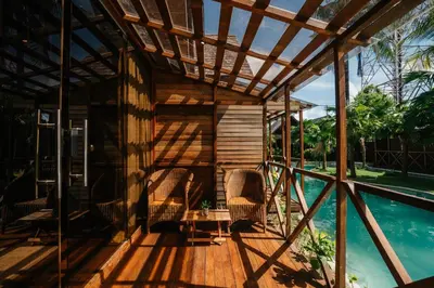 a wooden deck with chairs and a table next to a swimming pool at Wow Cozy Lagoon! in Nusa Dua