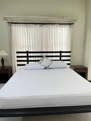 a large white bed in a bedroom with a window at Kubu In Dhana Sanur Guest House in Mantaak