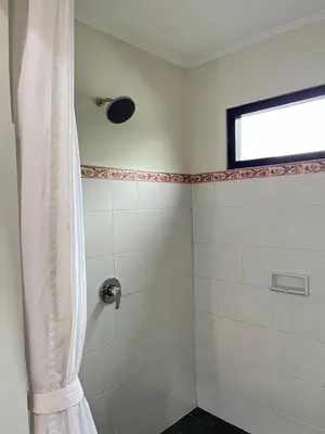 a bathroom with a shower with a shower curtain at Kubu In Dhana Sanur Guest House in Mantaak